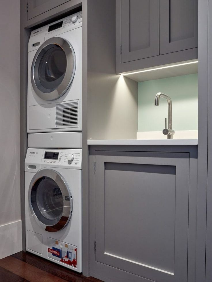 a washer and dryer are in the corner of a kitchen with gray cabinets