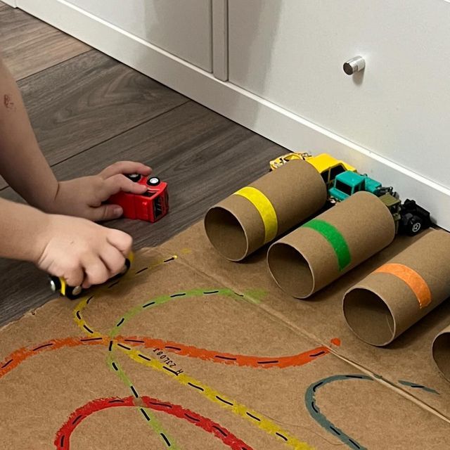 a child is playing with some construction paper tubes and toys on the floor in front of them