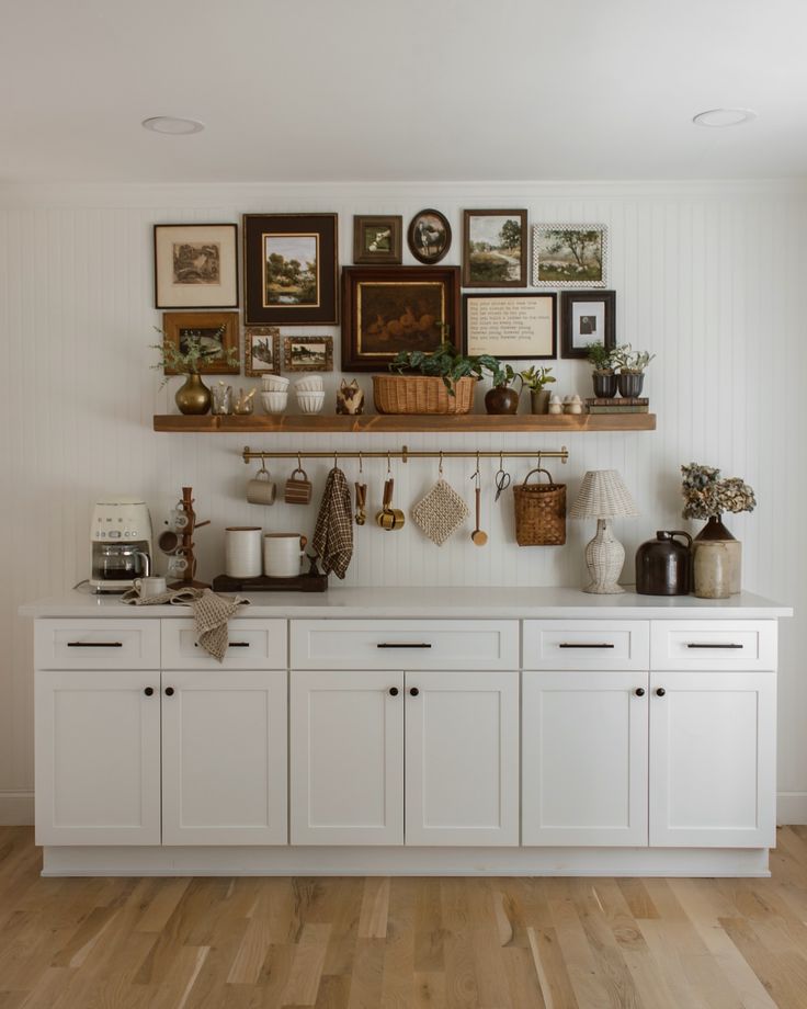 a kitchen with white cabinets and pictures on the wall above it's countertop