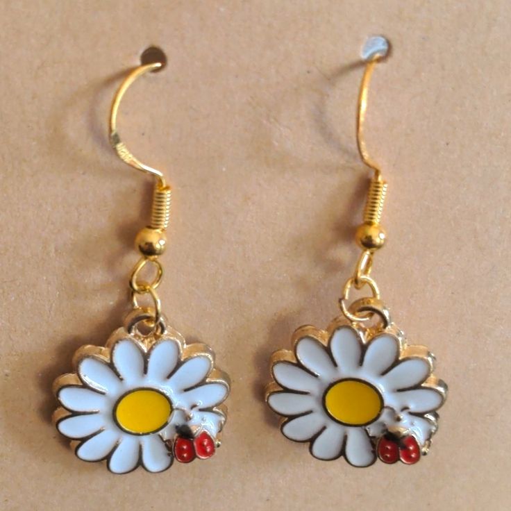 Cute Dangle Earrings Featuring A White Daisy With The Typical Yellow Center Being Visited By A Red Ladybug. Gold Tone Hooks. Measures Just Over 1.5 Inches From The Top Of The Hook To The Bottom Of The Flower. These Would Make A Great Stocking Stuffer Or Birthday Gift! New From Non-Smoking, Pet-Free Home. Summer Yellow Metal Jewelry, Casual Yellow Earrings Perfect For Gifts, Casual Yellow Earrings For Gift, Trendy Yellow Dangle Flower Earrings, Cute Red Earrings For Spring, Yellow Dangle Flower Earrings As Gift, Yellow Dangle Flower Earrings For Gift, Fun White Flower-shaped Jewelry, Casual Yellow Drop Earrings