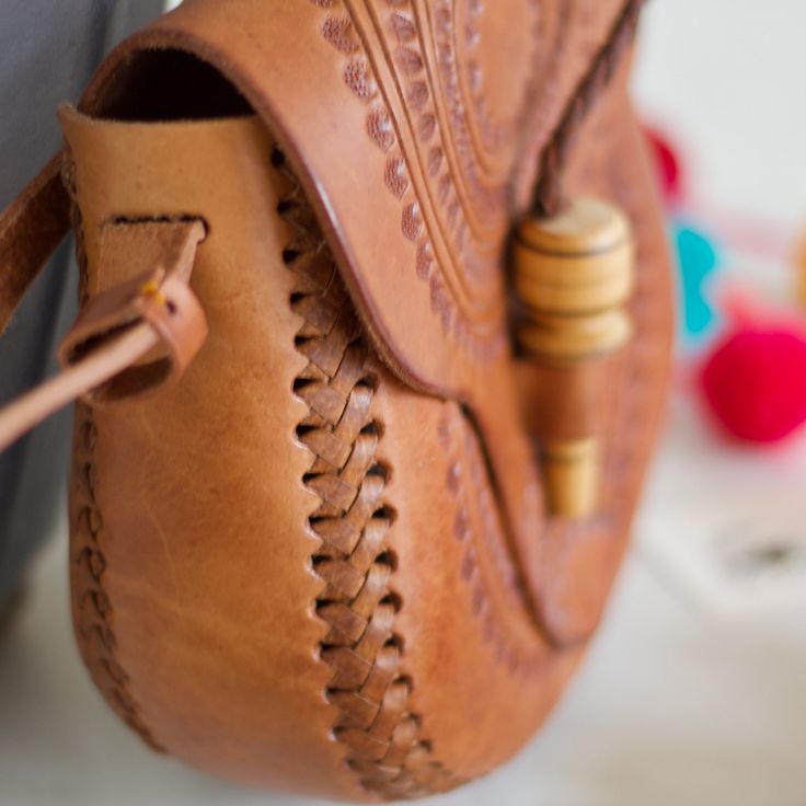 This beautiful sol design leather bag is hand-tooled by our artisan partner Daniel & family at his home work shop in Chiapas, Mexico. Each bag is individually hand-tooled onto quality thick leather, small variations in design and color can occur. Details: Can be worn over the shoulder or cross bodied. Adjustable strap for length- 55” 7 inch L x 8 inch H Wooden closure 100% Pure and Thick Cow Leather. All items are shipped from US Due to the handmade nature and the rawness of the leather, each ba Traditional Brown Leather Saddle Bag, Traditional Leather Satchel With Adjustable Strap, Traditional Leather Saddle Bag For Everyday Use, Artisan Leather Shoulder Bag For Festival, Traditional Leather Shoulder Bag For Everyday, Artisan Satchel With Adjustable Strap, Traditional Hand Tooled Shoulder Bag As A Gift, Traditional Leather Saddle Bag With Adjustable Strap, Artisan Shoulder Bag With Adjustable Strap