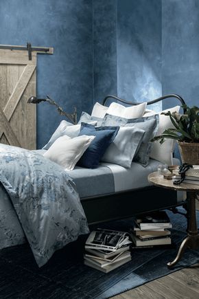 a bedroom with blue walls and white bedding has a plant in the corner next to it