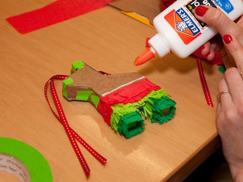 a person is decorating a gingerbread house with crepe paper and glue