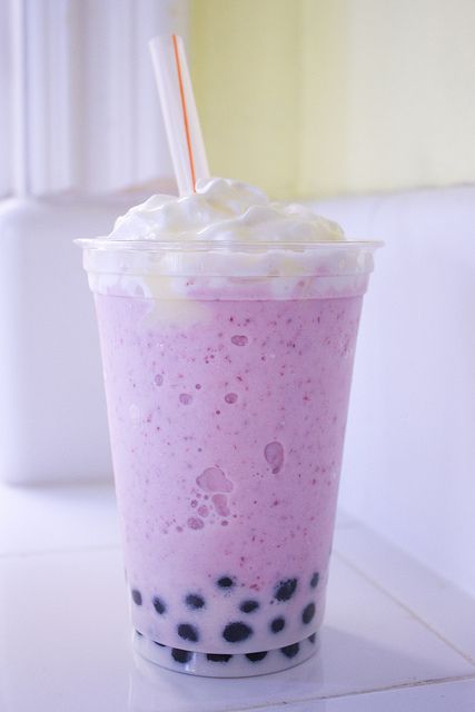 a pink drink with whipped cream and blueberries in it is sitting on a counter