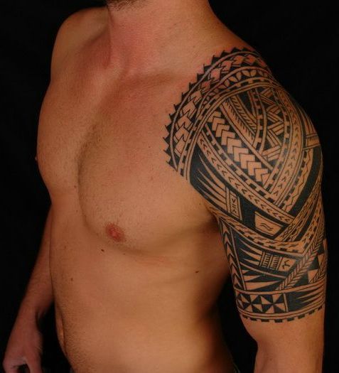 a man with a tattoo on his arm and chest is standing in front of a black background