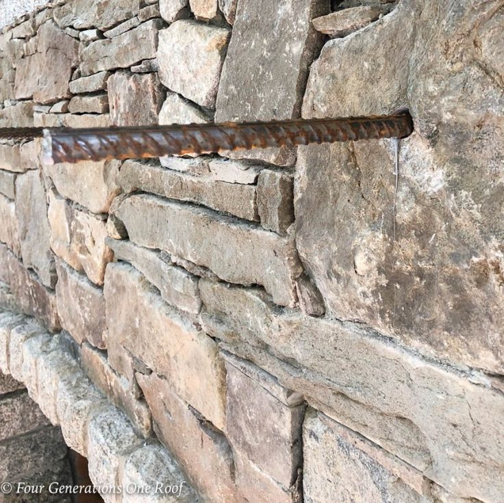 an old rusted metal bar is attached to a stone wall that has been built into it