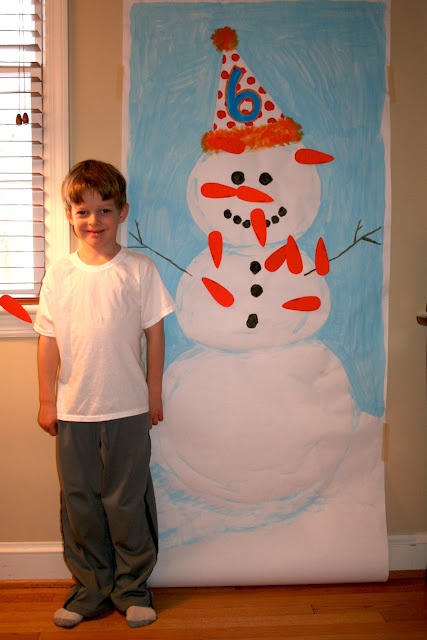 a young boy standing in front of a snowman painting