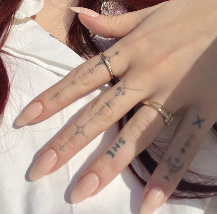 a woman's hand with tattoos on it and her ring in front of her face