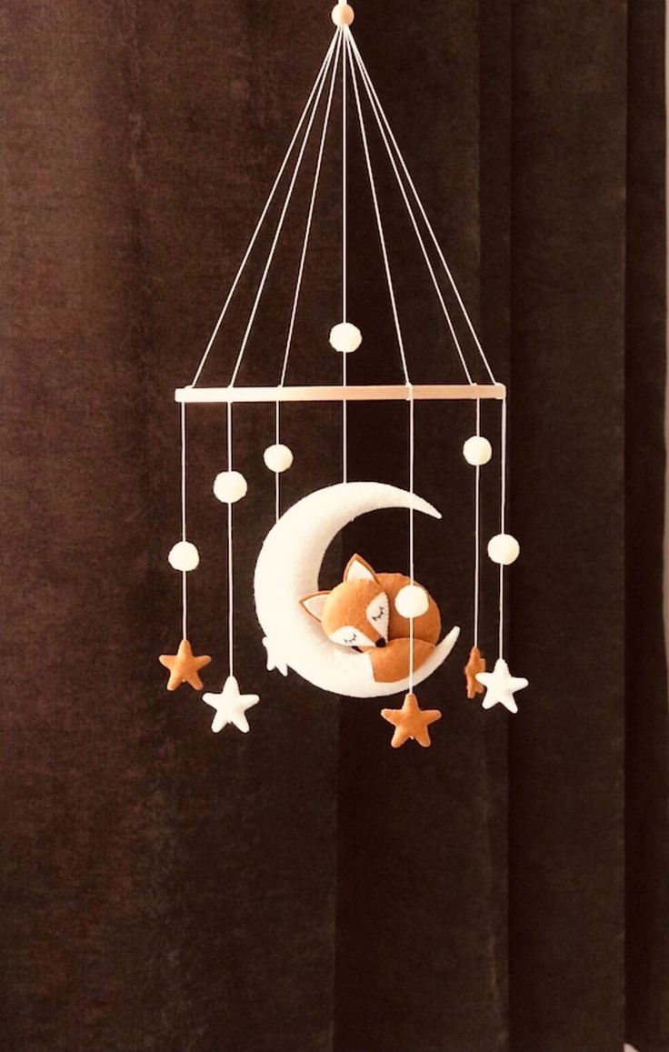 a baby crib mobile with a fox sleeping on the moon and stars hanging from it