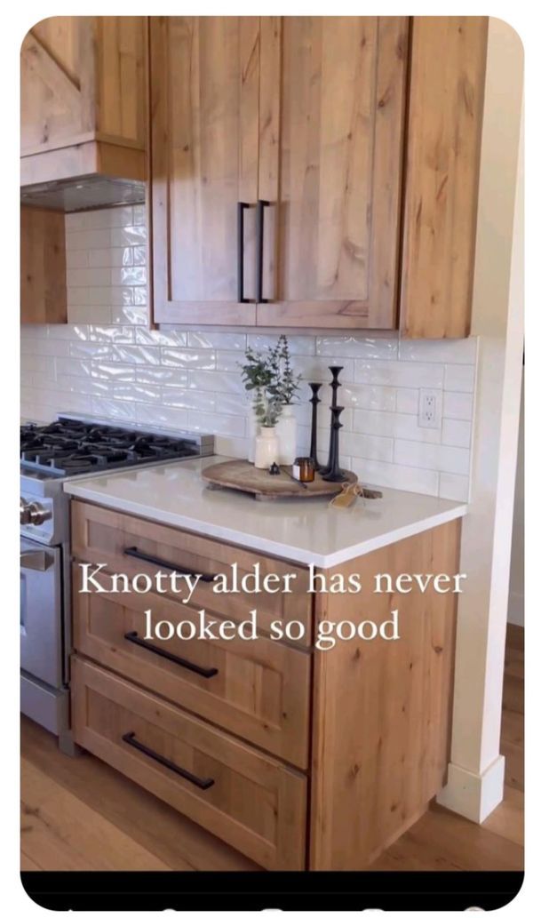 a kitchen with wooden cabinets and white tile backsplashing that says knotty alder has never looked so good