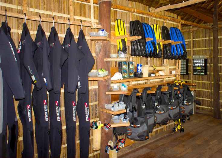 the inside of a surf shop filled with lots of wetsuits and boots on shelves