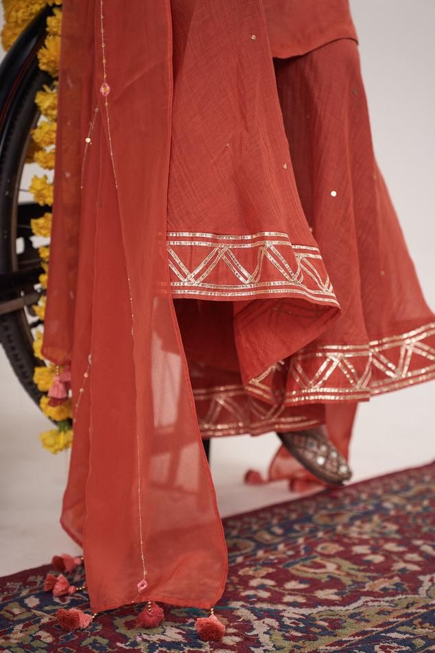 Rust orange resham, mirror and sequin hand embroidered kurta in gajji silk base. Paired with a gota embroidered sharara and dupatta with tassels.
Components: 3
Pattern: Embroidered
Type Of Work: Sequin, Resham, Mirror
Neckline: Round
Sleeve Type: Three-quarter
Fabric: Kurta: Gajji Silk, Sharara: Malai Chanderi, Dupatta: Organza
Color: Orange
Other Details: 
Model Height: 5ft, 6inches, wearing size M
Occasion: Mehendi and Puja - Aza Fashions Orange Traditional Drape Set With Dupatta, Orange Palazzo Set With Straight Kurta For Wedding, Orange Wedding Palazzo Set With Straight Kurta, Orange Sharara With Resham Embroidery In Traditional Drape, Orange Palazzo Set With Dabka Work And Straight Kurta, Traditional Orange Palazzo Set With Zari Work, Designer Orange Sharara With Straight Kurta, Traditional Orange Palazzo Set With Gota Work, Orange Designer Wear Sets With Traditional Drape