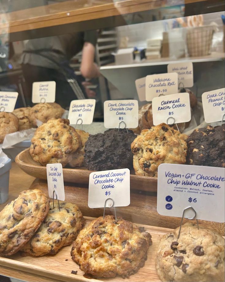 a display case filled with lots of cookies and muffins on top of wooden boards