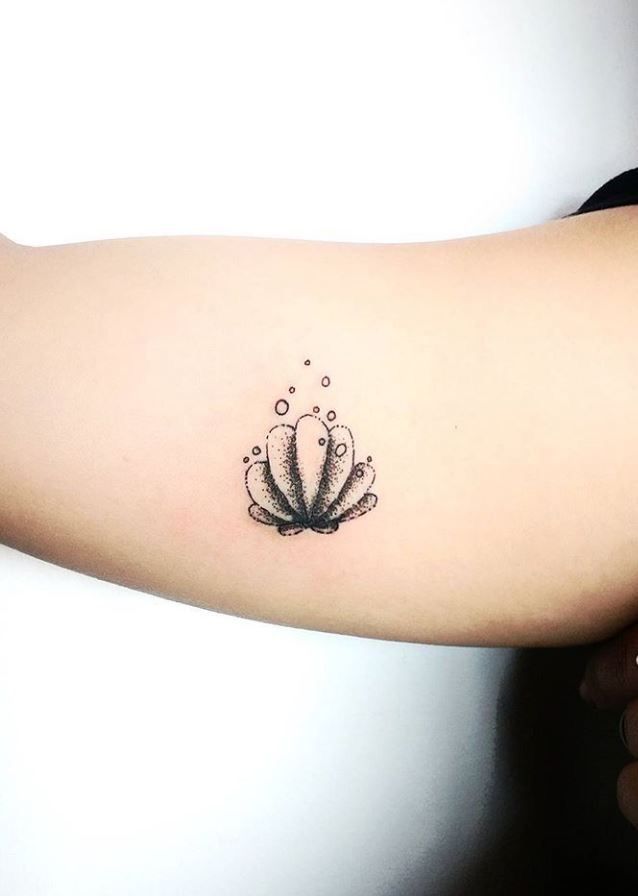 a woman's arm with a tattoo on it that has an image of a shell and bubbles