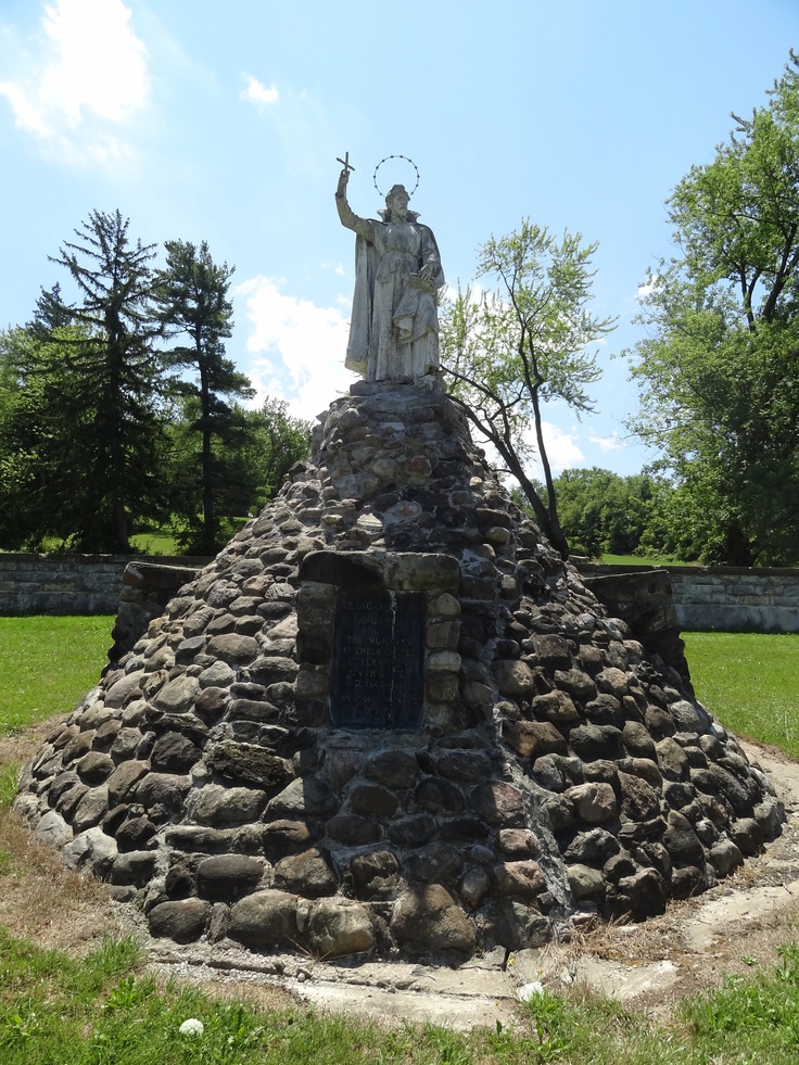 the statue is made out of rocks and has a man standing on top of it