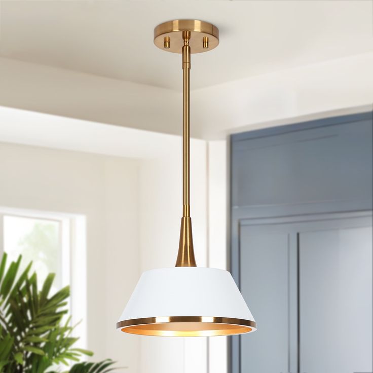 a white lamp hanging from the ceiling in a room with blue cabinets and potted plants