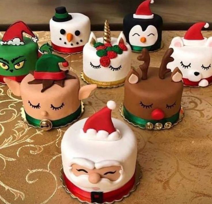 a table topped with lots of cakes covered in frosting and santa clause hats on top of each cake