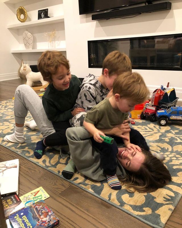 three children are playing with each other on the floor in front of a tv and bookshelf