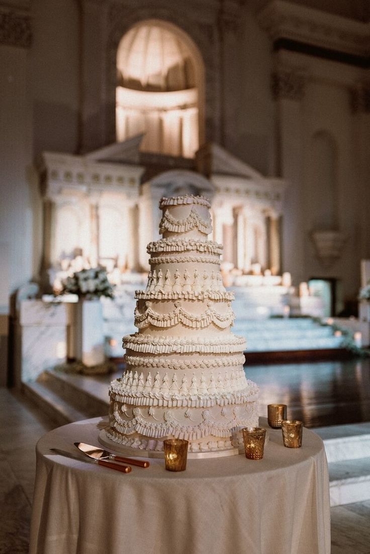 a wedding cake sitting on top of a table in a room filled with white linens