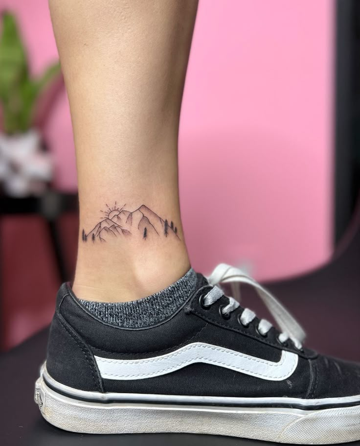 a woman's foot with a small mountain tattoo on the lower part of her ankle