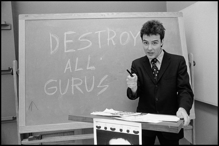 a man standing in front of a chalkboard giving a lecture on destroy all grus