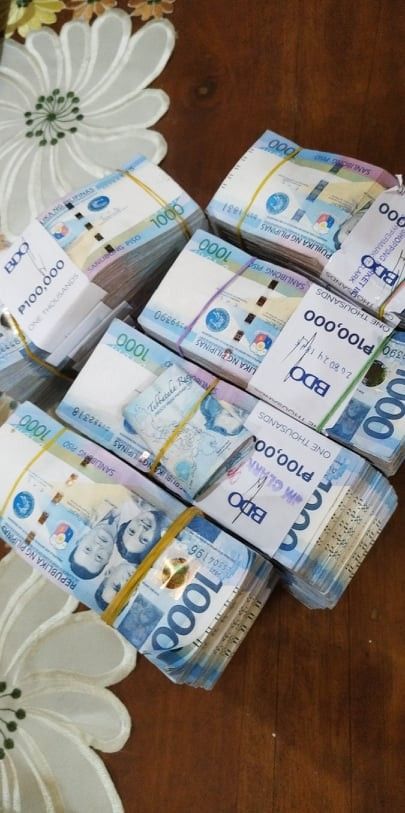 several stacks of mexican currency sitting on top of a wooden table next to white flowers