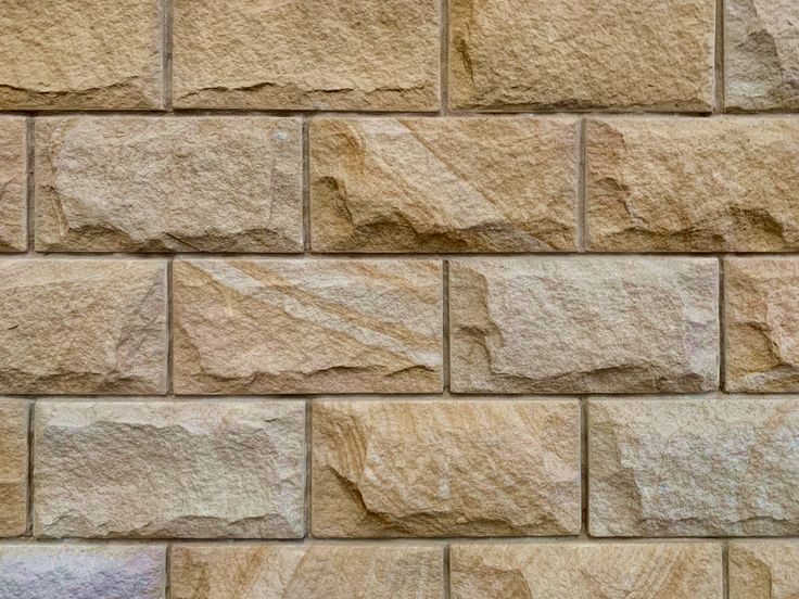 a close up view of a wall made out of tan colored stone blocks, with no mortar