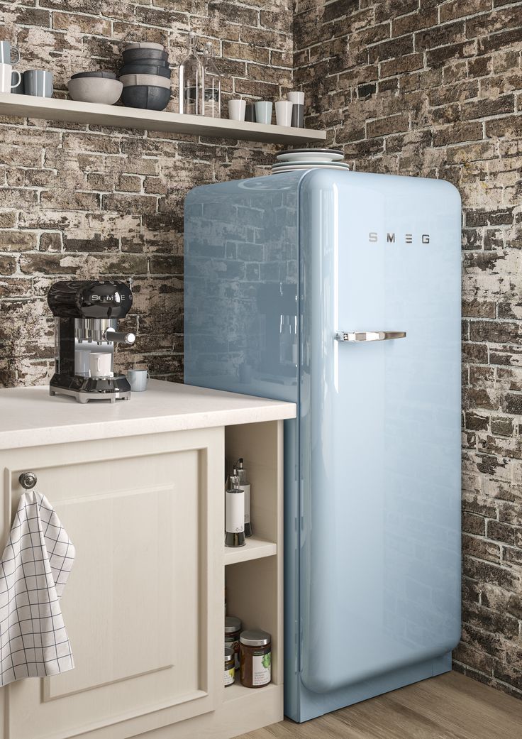 a blue refrigerator sitting next to a white counter top under a brick wall in a kitchen