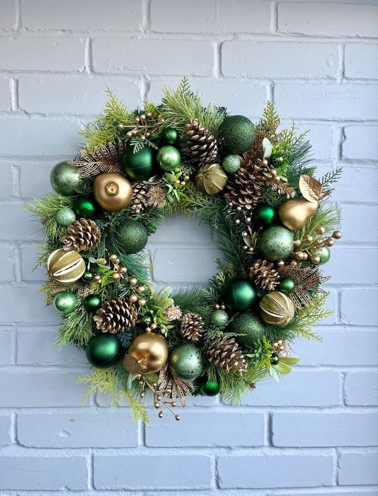 a christmas wreath on a brick wall with green and gold ornaments hanging from the front