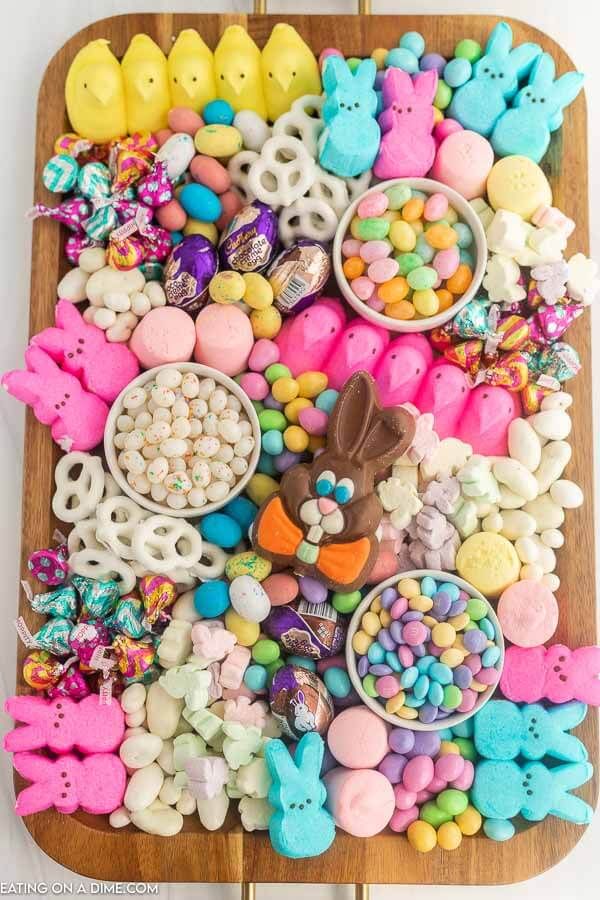 a wooden tray filled with lots of colorful candies and chocolate bunny ears on top of it