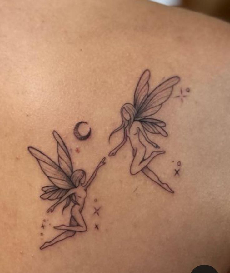 two fairy tattoos on the back of a woman's shoulder