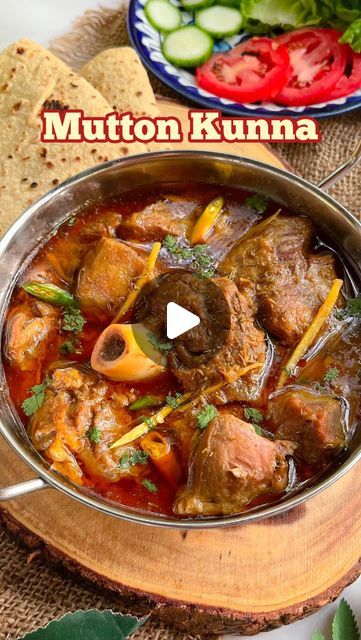 a bowl filled with meat and vegetables on top of a wooden table next to bread