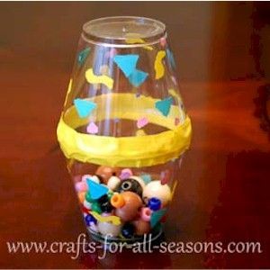 a plastic cup filled with lots of colorful balls and beads on top of a wooden table