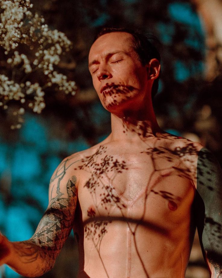 a man with tattoos on his chest holding a frisbee