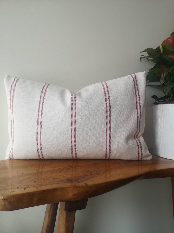 a white pillow sitting on top of a wooden table next to a potted plant