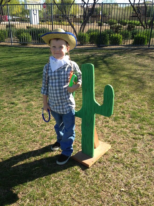 a young boy standing next to a green cactus