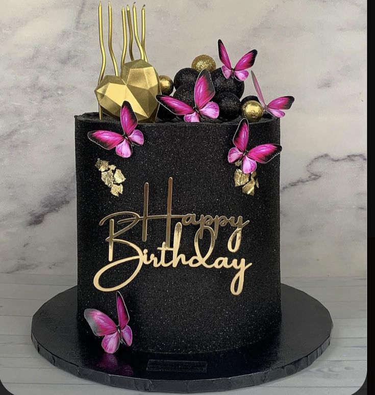 a black and gold birthday cake with pink flowers