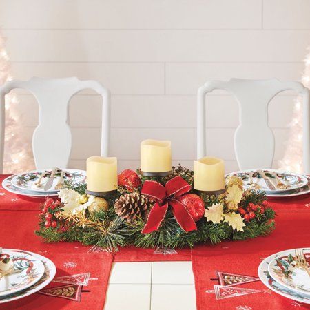 a christmas table setting with pine cones and candles