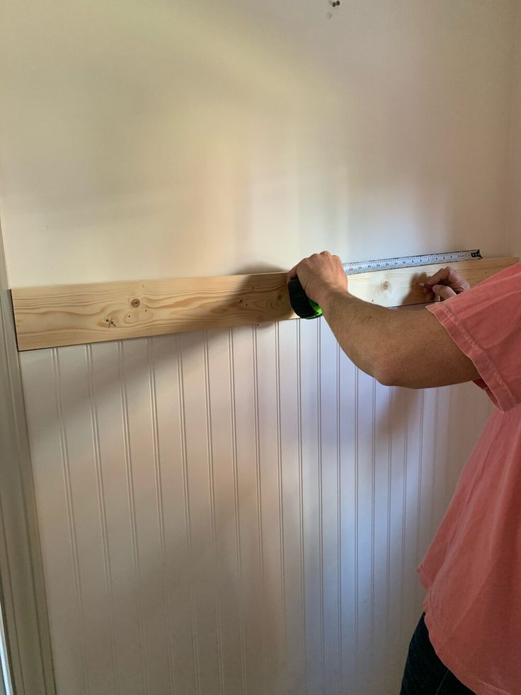 a man measuring the width of a wall with a tape measure on it's side