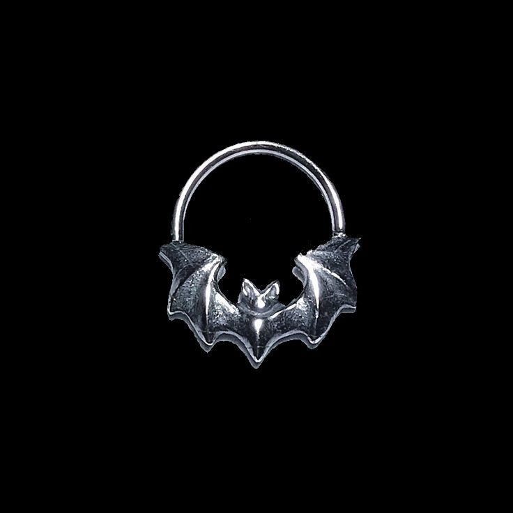 a silver ring with a bat on it's side in front of a black background