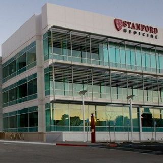 an empty parking lot in front of a large building with glass windows and the words stanford medical written on it