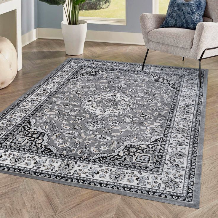 a large rug with an ornate design on the floor in a living room next to a chair and potted plant