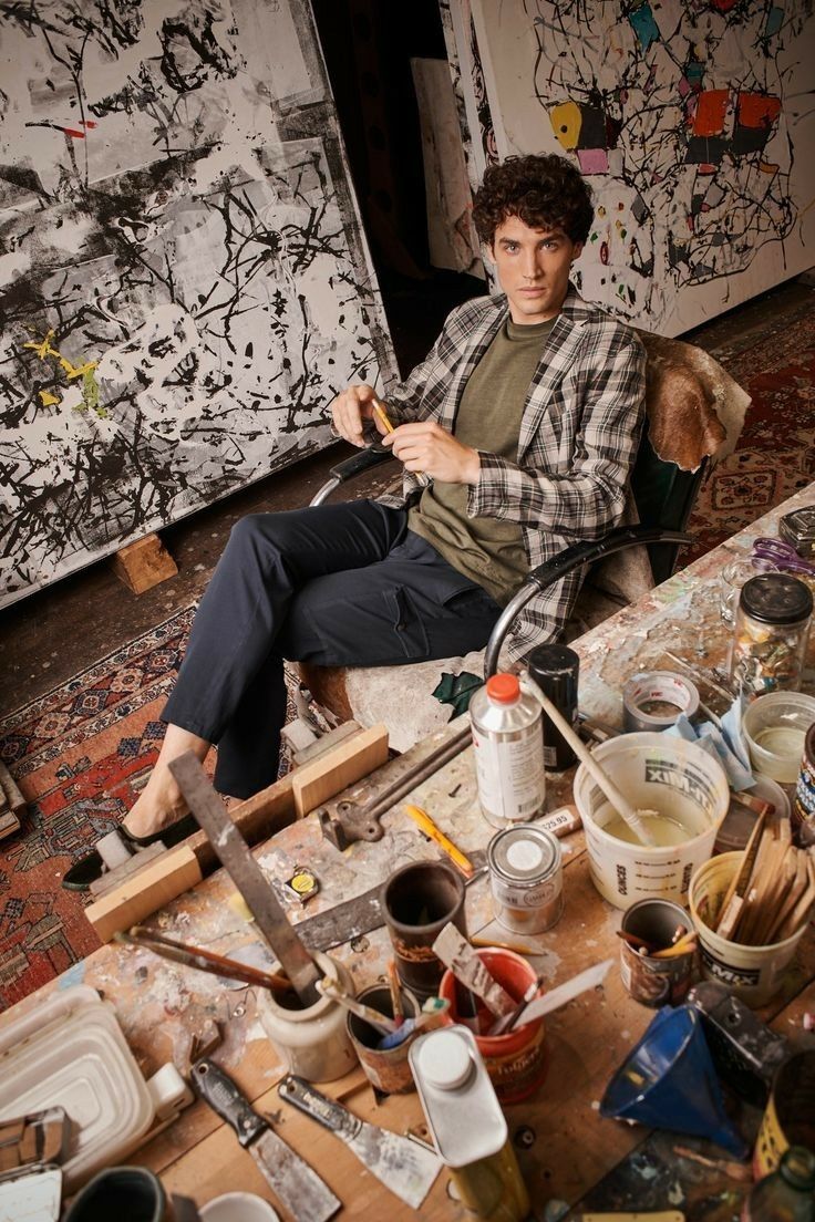 a man sitting in a chair surrounded by art supplies