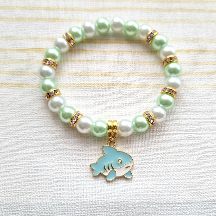 Cute shark beaded stretch bracelet. Perfect gift for any animal lover for a birthday or Christmas gift  These are great gifts for little girls aswel as adults, you will find matching items in my store. *The bracelets are available for adults and children. Adults measure approximately 7.5inches unless a note is made. Children sizes vary depending on age of child. *The bracelets are made using 8mm glass pearl beads in any colours of your choice. *In between the beads are gold rhinestone beads to g Themed Green Beaded Bracelets For Gifts, Playful Green Stretch Bracelet As Gift, Themed Green Beaded Bracelets As Gift, Green Themed Beaded Bracelets As Gifts, Ocean-inspired Adjustable Charm Bracelet As Gift, Ocean-inspired Adjustable Charm Bracelet Gift, Playful Blue Stretch Bracelet For Gift, Playful Blue Stretch Bracelet As Gift, Playful Blue Stretch Bracelet Gift