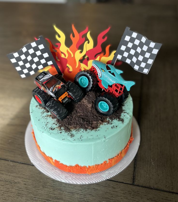 a birthday cake decorated with monster trucks and flags