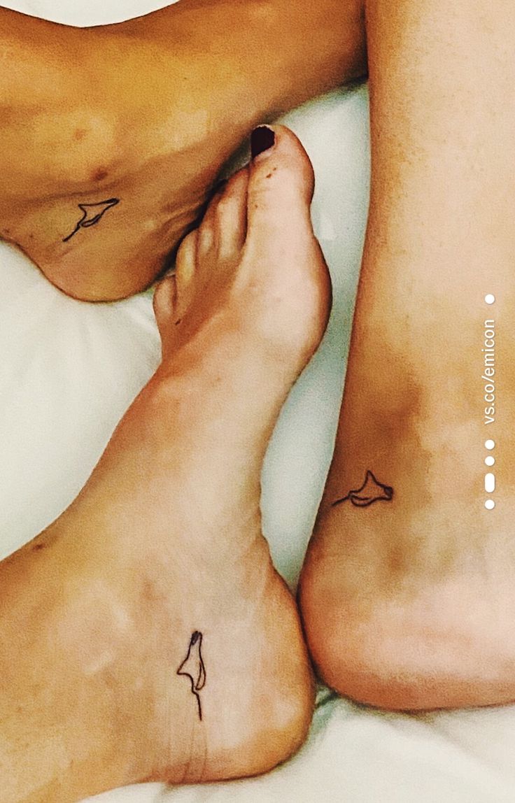 two people with tattoos on their legs laying in bed next to each other and one has a small bird tattoo on his left leg