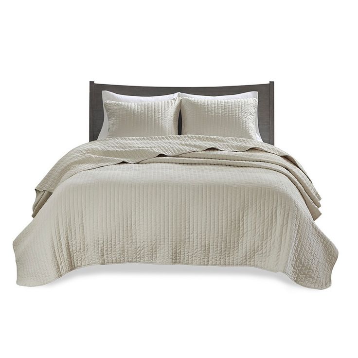 a white bed with two pillows on top of it and a blanket in the middle