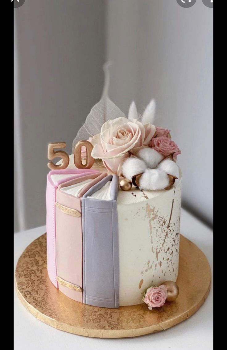 a cake decorated with books and flowers on a wooden platter that reads 50 years