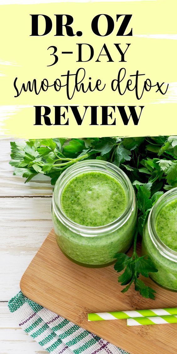 two jars filled with green smoothie sitting on top of a wooden cutting board next to greens