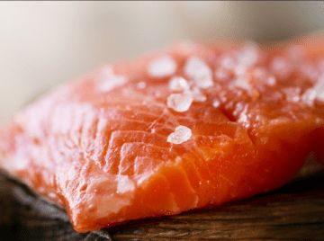 a piece of salmon sitting on top of a wooden table